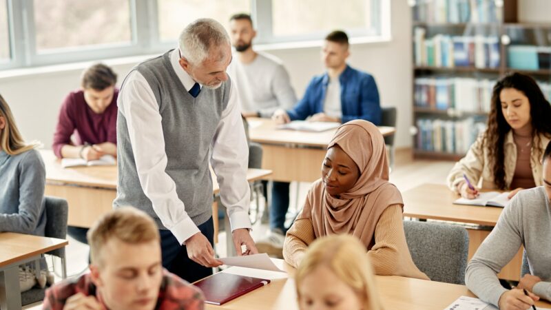 Senior professor talking to African American Muslim student during a class in the classroom.