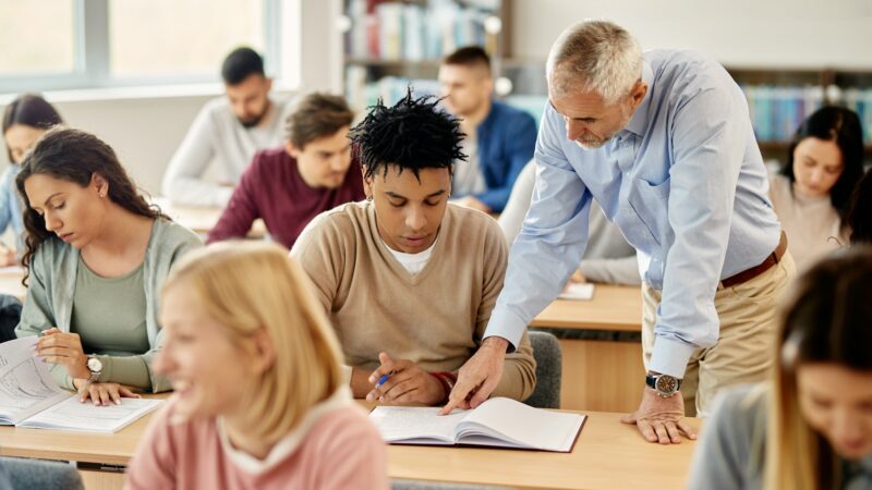 Young black student learning with teacher's help during a class at the university.